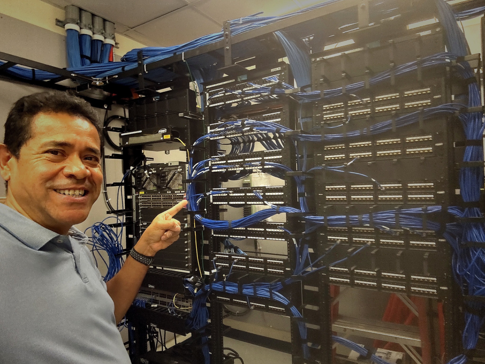 R3QUESTS technician beside a network rack installation